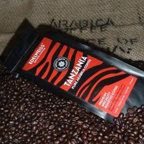 Edelweiss Tanzania Pure Arabica Coffee branded bag resting on roasted beans